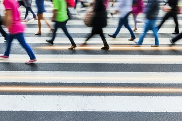 Creative light trail effect of pedestrians crossing a busy street in the city during evening rush hour