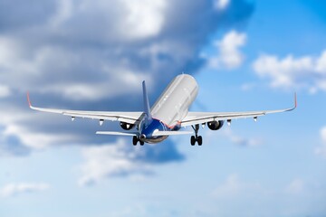 Commercial airplane flying in blue sky, preparing for landing.