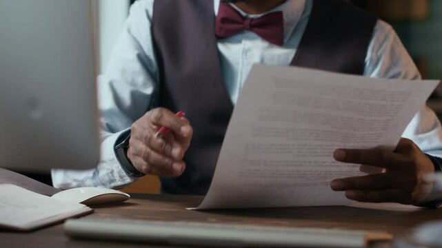 Tilt up shot of African American male educational specialist marking students works at table indoors