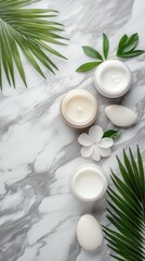 White stones and palm leaves are arranged on a gray marble table, showcasing spa cosmetic products in a peaceful flat lay setting