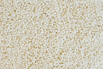 white mother-of-pearl small seed glass beads close-up. materials for beading.