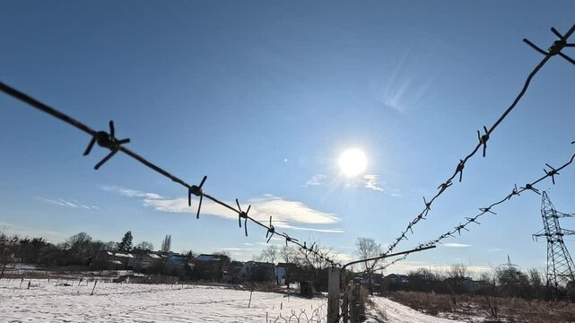 Bright winter sunny day. Blue sky and barbed wire.