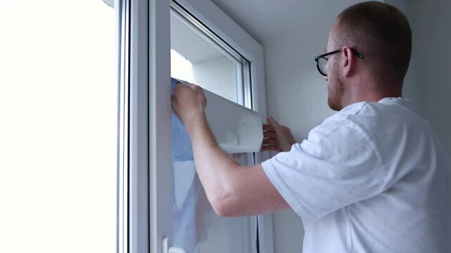 Man takes sun protection film off from the windows glass. 4K