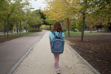 redhead girl hiking park with backpack. child backpacker walking in nature. Summer. Horizontal	
