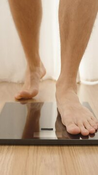 Vertical video. Barefoot Person Standing in Front of Digital Scale on Wooden Floor with Curtains in Background