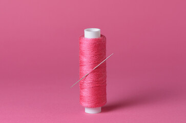 One single pink thread spool with needle close-up background with copy space for text