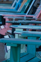 Fototapeta premium A selection of painted wooden chairs aligned beside a walkway in an outdoor park setting, showcasing various vibrant colors and patterns.