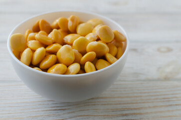 Lupin beans in a white bowl on a wooden table. Italian food. Type of legumes. Healthy food concept. Horizontal orientation. Selective focus. Copy space.