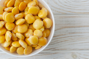 Lupin beans in a white bowl on a wooden table. Italian food. Type of legumes. Healthy food concept. Horizontal orientation. Selective focus. Copy space. Top view