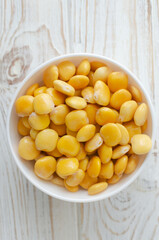 Lupin beans in a white bowl on a wooden table. Italian food. Type of legumes. Healthy food concept. Vertical orientation. Selective focus. Top view