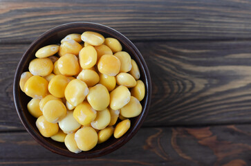 Lupin beans in a brown bowl on a wooden table. Italian food. Type of legumes. Healthy food concept. Horizontal orientation. Selective focus. Copy space. Top view
