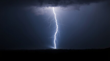 Dramatic lightning strike illuminating dark landscape during thunderstorm
