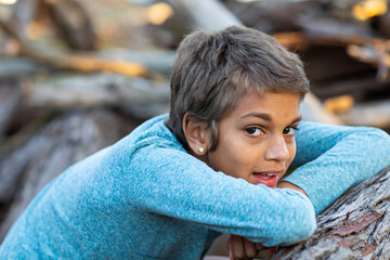 kid resting chin on her arms in the bush
