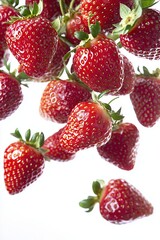 Fresh ripe strawberries floating in mid-air against a bright white background