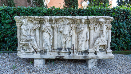 Human figures carved in ancient marble sarcophagus in ruins exhibited at an italian garden