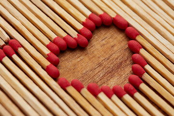 Close-up of heart made of match sticks on wooden background - Love concept