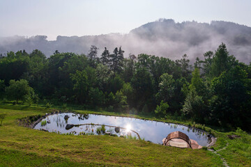 Pretty wooden pier at natural swimming pond or pool - NSP - purifying water without chemicals through biological filters and plants