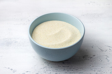 Light blue ceramic bowl filled with semolina sits on a textured light grey marble surface