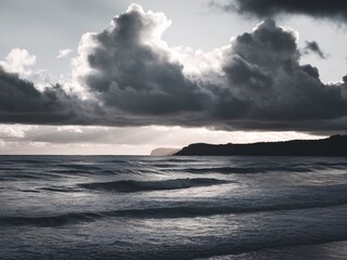 Fototapeta premium Moody ocean scene with dark clouds and gentle waves, creating a serene atmosphere.