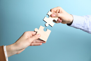 Business strategy and teamwork concept. Partners putting puzzle pieces together on light blue...