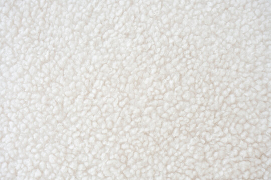 A highly detailed close-up of fluffy white sherpa fleece with a textured surface. This fabric, crafted from recycled polyester, offers warmth and comfort for sustainable fashion, outerwear, textiles.
