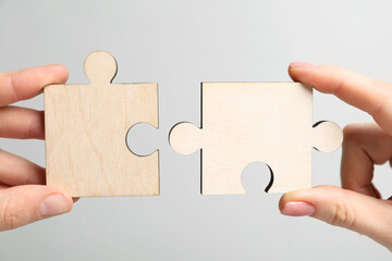 Business strategy and teamwork concept. Partners putting puzzle pieces together on grey background,...