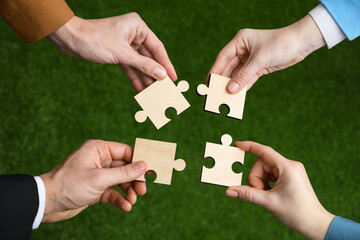 Teamwork. Group of people putting puzzle pieces together on blurred background, top view