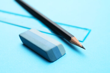 Eraser, pencil and ruler on light blue background, closeup