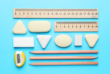 Erasers and other stationery on light blue background, flat lay