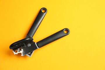 One can opener on yellow background, top view. Space for text