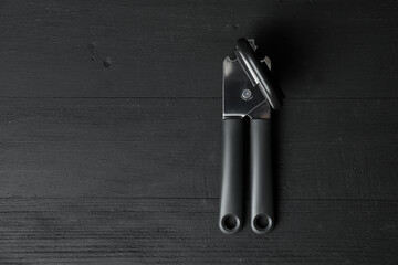 One can opener on black wooden table, top view. Space for text