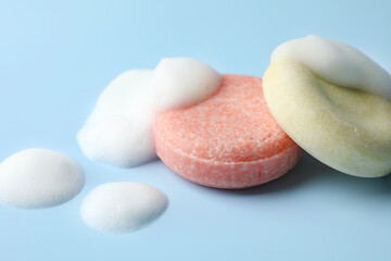 Soap bars with foam on light blue background, closeup