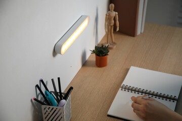 Woman working at desk with LED lamp on wall, closeup