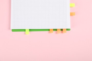 Notebook with colorful tabs on pink background, top view. Space for text