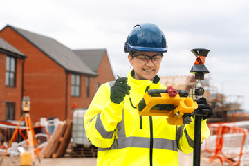 Portrait of happy Female Construction worker using surveying equipment at a residential site