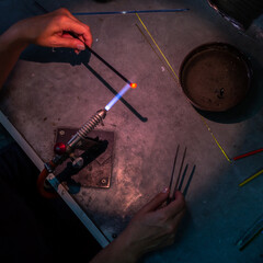 Glass bead making process with torch flame.