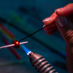 Glassworking process with molten glass in artisan's hands. 