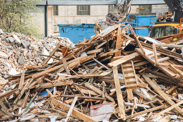 Construction debris piled high at a demolition site with machinery nearby