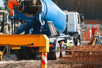 Construction site featuring a blue concrete mixer truck and steel reinforcement bars