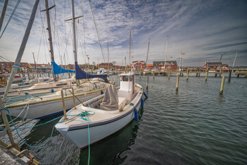 Fototapeta premium Marina with Boats Docked Near Red Waterside Buildings on a Sunny Day, Juelsminde, Denmark