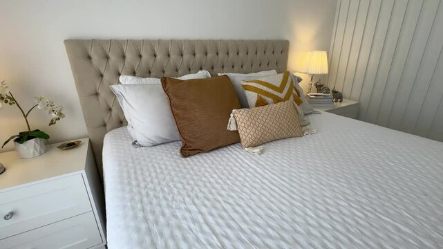 cama arrumada com cabeceira de luxo capitone e tons decora&ccedil;&atilde;o amarela e tons marrons 