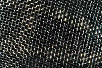 Monochrome texture of a shiny metal colander or grate. Abstract background.