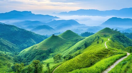 Obraz premium Serene Landscape of Rolling Green Hills Under a Soft Blue Sky with Distant Mountains