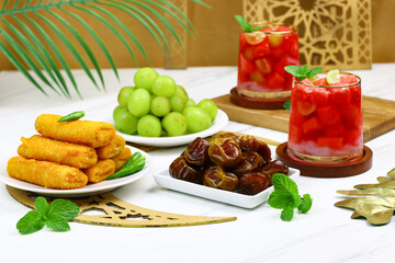 Typical Indonesian iftar menu in ramadan month. Fruit ice, dates fruit, risoles, and grapes. Islamic background with white marble color.