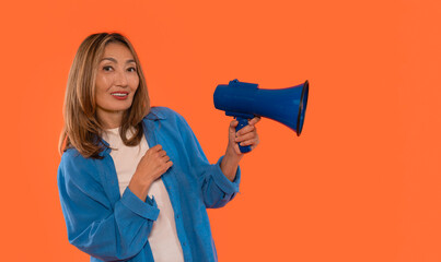 Woman enthusiastically holding blue megaphone against a vibrant orange background while promoting...