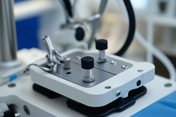 Close-up image of a medical device with metallic knobs and components, part of an advanced surgical system in a clinical setting.