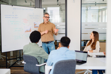 Senior business leader delivering a strategic presentation to a diverse and engaged team. A modern corporate setting focused on business growth, teamwork, and leadership development.