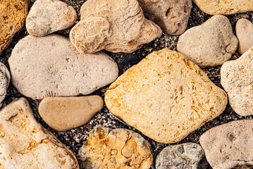 Colorful collection of smooth stones scattered on a sandy beach during midday under bright sunlight