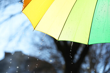 Open bright umbrella under pouring rain outdoors, closeup