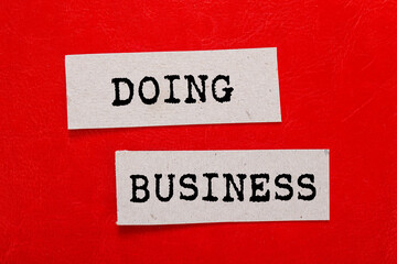 Doing business message written on paper pieces on red background. Conceptual doing business symbol. Copy space.